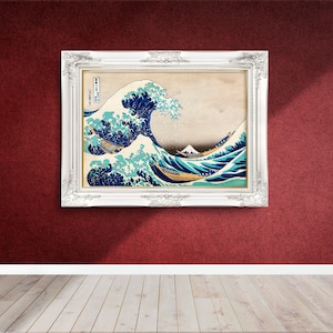 May include: A white framed print of a famous Japanese woodblock print depicting a large wave crashing. The wave is blue and white with a mountain in the background. The print is titled "The Great Wave off Kanagawa".