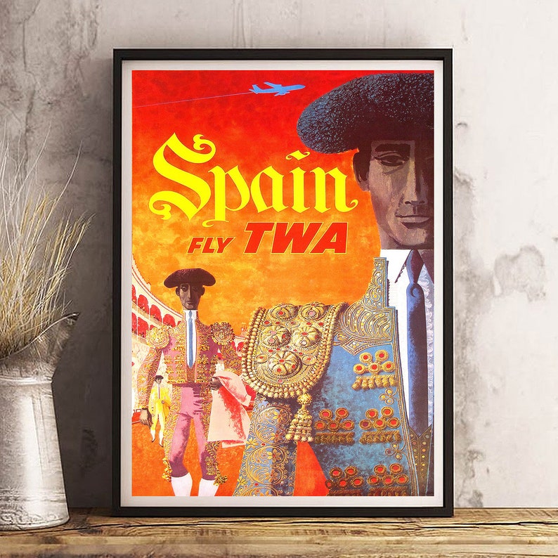Puede incluir: Un cartel de viaje vintage que anuncia un viaje a Espa&ntilde;a con las aerol&iacute;neas TWA. El cartel presenta a un torero con un traje tradicional, con una capa roja y dorada, y una plaza de toros en el fondo. El texto del cartel dice "Espa&ntilde;a FLY TWA".