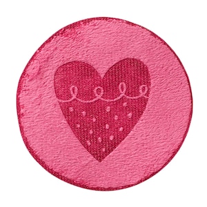 Pode incluir: Um emblema circular com uma superfície rosa texturizada apresentando um design de coração rosa mais escuro no centro. O coração é decorado com uma linha festonada no topo e um padrão de pequenos pontos brancos na parte inferior.