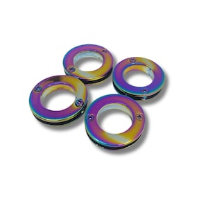 Peut inclure: Quatre œillets métalliques circulaires dotés d'une finition irisée aux couleurs de l'arc-en-ciel. Chaque œillet présente une surface lisse et réfléchissante avec deux petites vis placées sur les côtés opposés de l'anneau pour fixer l'ensemble.