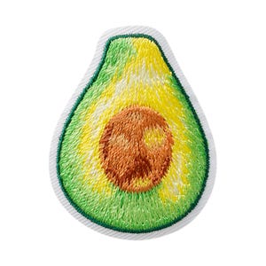 Op de afbeelding: Een geborduurde patch in de vorm van een gehalveerde avocado. Het ontwerp toont een bruine pit in het midden, omringd door lichtgroen en geel vruchtvlees, met een donkergroene rand en een witte stoffen afwerking rondom de avocado-vorm.