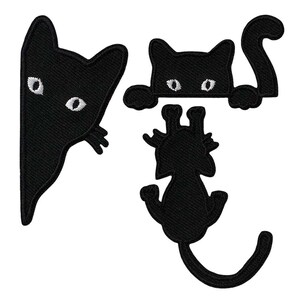 May include: Three black cat embroidered patches. One patch shows a cat head peeking from the side, another shows a cat head with paws resting on a ledge and a raised tail, and the third shows a cat hanging by its front paws with a long tail.