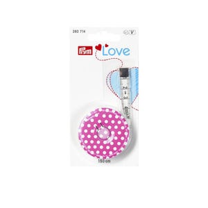 Può includere: Un metro a nastro retrattile rotondo rosa con pois bianchi e un disegno di coccinella al centro. Il metro è confezionato su un cartoncino bianco con l'etichetta Prym Love, indica 150 cm e mostra un segmento di nastro bianco visibile.