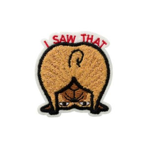 Op de afbeelding: Een geborduurde patch met een beige mopshond van achteren gezien, met de kop tussen de poten en kijkend met grote ogen. De tekst I SAW THAT is in het rood boven de hond geborduurd, alles wit omlijnd op een zwarte rand.