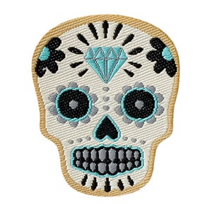 Pode incluir: Um emblema bordado em forma de caveira com uma base cor de creme. O design apresenta um diamante azul-claro na testa, órbitas florais pretas e azul-claras, um nariz preto e dentes cinzentos delineados com fio azul-claro em toda a volta.