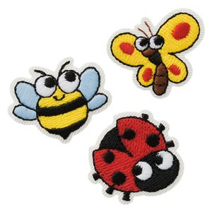 Pode incluir: Três emblemas bordados com insetos de desenho animado: uma abelha listrada de amarelo e preto com asas azul-claras, uma borboleta amarela com detalhes vermelhos e corpo marrom, e uma joaninha vermelha com pintas pretas, todos com bordas brancas.