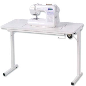 May include: A white sewing machine sits on a white adjustable sewing table. The table features a rectangular cutout for the machine, a manual hand crank mechanism on the right side, and four thin legs with black feet. The machine has a digital display.