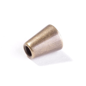 Könnte beinhalten: Eine kleine, kegelförmige Kordelendkappe mit gebürstetem Antik-Messing-Finish. Das Metallteil verfügt über eine glatte, konisch zulaufende Außenfläche und eine kreisförmige Öffnung am schmaleren Ende, die zum Sichern von Kordelenden dient.