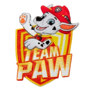 Pode incluir: Um emblema bordado apresentando um filhote de dálmata branco usando um capacete de bombeiro vermelho, acenando com uma pata. O filhote está posicionado sobre um emblema amarelo e vermelho em forma de escudo com o texto branco TEAM PAW.
