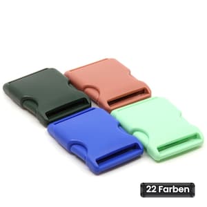 Puede incluir: Cuatro hebillas de plástico de liberación lateral en verde oscuro, terracota, azul y verde menta. Cada hebilla tiene una forma rectangular con una ranura para cinta. Una pequeña etiqueta negra en la esquina inferior derecha muestra 22 Farben.