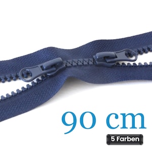 Op de afbeelding: Een donkerblauwe kunststof ritssluiting met twee bijpassende schuivers op een stoffen band. De tekst 90 cm is in het blauw gedrukt en een klein zwart rechthoekig label toont de tekst 5 Farben, wat duidt op vijf beschikbare kleuren.