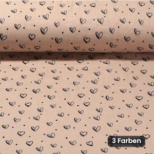 Könnte beinhalten: Ein hellbeiger Stoff mit einem sich wiederholenden Muster aus kleinen, handgezeichneten schwarzen Herzen und winzigen schwarzen Punkten, die über die Oberfläche verteilt sind. Unten rechts zeigt ein dunkles Etikett den Text 3 Farben.