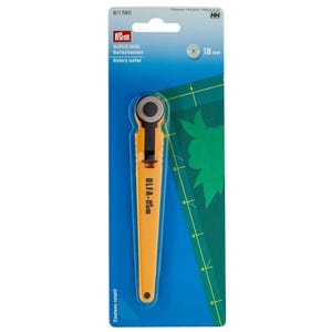 Pode incluir: Um cortador rotativo Prym Super Mini com uma lâmina de 18 mm, apresentando um cabo amarelo brilhante e um protetor de lâmina preto. A ferramenta é exibida na sua embalagem original azul, com as marcas OLFA e Prym impressas.