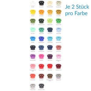 Op de afbeelding: Een verzameling kleine plastic koordstoppers gerangschikt in een raster, met een grote verscheidenheid aan effen kleuren waaronder wit, zwart, geel, oranje, groen, blauw, roze, rood en grijs. Elke koordstopper heeft twee gaten voor een koord.