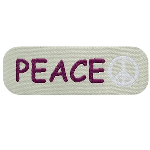 Pode incluir: Um emblema bordado retangular com cantos arredondados sobre um fundo bege claro. A palavra PEACE está bordada com fio roxo escuro, seguida por um ícone circular branco de símbolo da paz no lado direito do emblema de tecido.