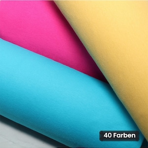 Könnte beinhalten: Drei gefaltete Stofflagen in den Farben leuchtendes Pink, Hellblau und sanftes Gelb. Ein kleines schwarzes rechteckiges Etikett in der unteren rechten Ecke zeigt den weißen Text 40 Farben, was auf eine Auswahl an verfügbaren Farboptionen hinweist.