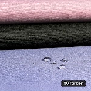 Può includere: Tre strati di tessuto in rosa chiaro, nero e azzurro sono impilati verticalmente. Il tessuto azzurro presenta piccole gocce d'acqua sulla superficie, indicando resistenza all'acqua. Un'etichetta nera mostra il testo 38 Farben.
