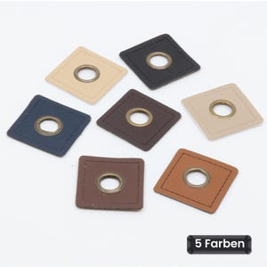 Könnte beinhalten: Sieben quadratische Aufnäher in Schwarz, Dunkelblau, Dunkelbraun, Hellbraun und Beige, jeweils mit einer mittigen Metallöse und abgesteppten Rändern. Ein schwarzes rechteckiges Etikett unten rechts zeigt den Text 5 Farben.