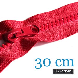 Könnte beinhalten: Ein leuchtend roter Kunststoffreißverschluss mit passendem rotem Schiebergriff. Das Reißverschlussband hat eine gewebte Struktur und die Zähne sind aus geformtem Kunststoff. Der Text 30 cm und 36 Farben ist unten rechts im Bild zu sehen.