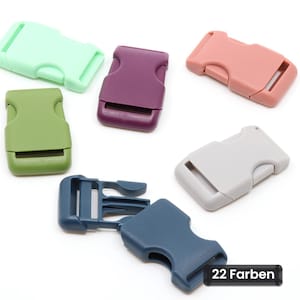 Puede incluir: Una colección de seis hebillas de plástico de liberación lateral en varios colores, incluyendo verde menta, verde oliva, morado oscuro, rosa empolvado, gris claro y azul marino. Una hebilla azul marino se muestra separada. El texto dice 22 Farben.