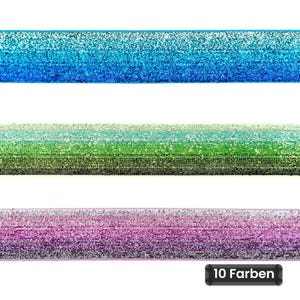 Op de afbeelding: Drie horizontale stroken elastisch lint met een glinsterende textuur. De bovenste strook is blauw, de middelste strook verloopt van lichtgroen naar donkergroen en de onderste strook is paars. Een zwart label toont de tekst 10 Farben.