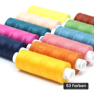 May include: A collection of sewing thread spools in various colors including yellow, peach, teal, magenta, navy blue, orange, green, and brown. Each spool has a white core with the text PREMIUM visible. A black label displays the text 53 Farben.