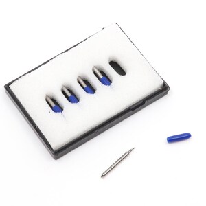 May include: A black rectangular storage case containing white foam with five slots, four of which hold silver metal cutting blades with blue protective caps. One additional silver blade and one loose blue protective cap lie outside the case.