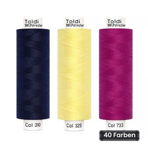 Puede incluir: Tres carretes de hilo Toldi 100% poliéster en azul marino, amarillo pálido y magenta. Cada carrete tiene una etiqueta blanca con la marca, composición y código de color: Col 310, Col 325 y Col 733. Una etiqueta negra indica 40 Farben.