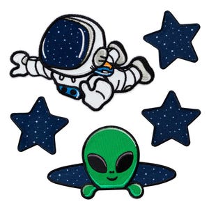 Op de afbeelding: Een set geborduurde patches met een witte astronaut in een ruimtepak met een donkerblauwe helm, een groen alienhoofd met grote zwarte ogen en drie donkerblauwe stervormige patches met kleine witte spikkels als sterren.