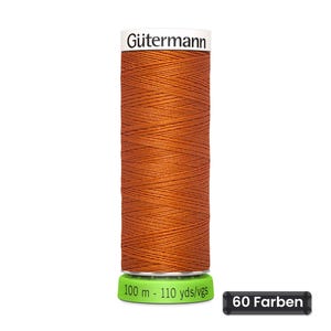 Könnte beinhalten: Eine Spule mit rostorangem Nähgarn von Gütermann. Das weiße Etikett oben zeigt den Markennamen. Der grüne Sockel trägt den Text 100 m - 110 yds/vgs. Ein kleines schwarzes rechteckiges Schild rechts zeigt den Text 60 Farben.