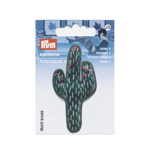 Puede incluir: Un parche bordado en forma de cactus de color verde oscuro con detalles de puntadas verticales blancas y pequeños acentos rosas. El parche está montado sobre un soporte de cartón rectangular de la marca Prym con gráficos y texto en azul y blanco.