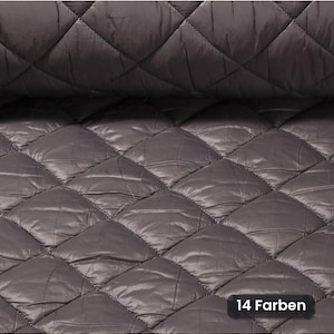 Könnte beinhalten: Ein dunkelgrauer Steppstoff mit einem sich wiederholenden Rautenmuster und abgesteppten Nähten. Das Material hat eine glatte, leicht reflektierende Oberfläche. Ein kleines schwarzes Etikett in der unteren rechten Ecke zeigt den Text 14 Farben.
