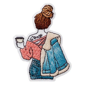 Pode incluir: Um emblema bordado representando uma figura vista de costas com um coque castanho, vestindo uma blusa rosa de manga comprida com costas cruzadas, calças de ganga azuis e segurando uma chávena de café. A figura tem uma tatuagem nas costas com a palavra Sexy.