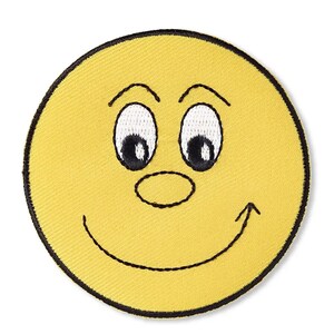 Può includere: Una toppa ricamata circolare raffigurante un volto giallo con un bordo nero cucito. Il design include due occhi ovali bianchi con pupille nere, sopracciglia nere arcuate, un piccolo naso ovale e una linea nera curva che forma un sorriso.