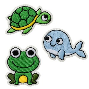 Op de afbeelding: Drie geborduurde stoffen patches met cartoonfiguren: een groene schildpad met een gele rand, een lichtblauwe walvis met een witte buik en een groene kikker met een gele buik. Elke patch heeft een witte gestikte rand en gedetailleerd borduurwerk.