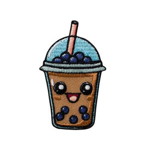 Può includere: Una toppa ricamata raffigurante un bubble tea color marrone chiaro in un bicchiere trasparente con coperchio azzurro e cannuccia. Il bicchiere presenta un volto sorridente con grandi occhi neri, guance rosate e perle di tapioca blu scuro.