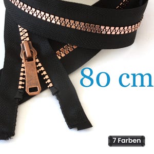 Op de afbeelding: Een zwarte rits met koperkleurige metalen tanden en een bijpassende koperkleurige ritstrekker. De rits is 80 cm lang. De tekst 80 cm en 7 Farben is zichtbaar op de afbeelding, wat de lengte en de kleurvariatie aangeeft.