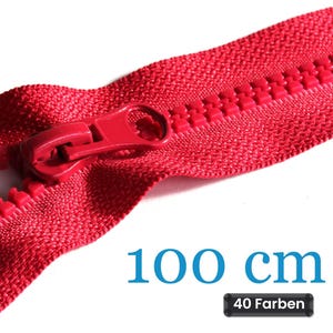 Op de afbeelding: Een felrode plastic rits met een bijpassende ritstrekker en tanden. Het ritsband is gemaakt van geweven stof. De tekst 100 cm en 40 Farben is zichtbaar in het onderste gedeelte van de afbeelding, wat de lengte en de variëteit aangeeft.