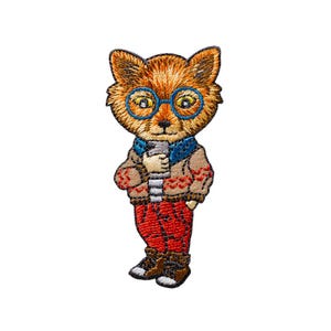 Pode incluir: Um emblema bordado com uma raposa laranja usando óculos de aro azul, um suéter bege com padrões vermelhos, um cachecol azul e calças vermelhas. A raposa segura um pequeno objeto retangular cinza entre as suas mãos.