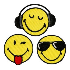 Peut inclure: Trois écussons brodés circulaires représentant des visages souriants jaunes. Un visage porte un casque noir, un autre fait un clin d'œil avec la langue rouge tirée, et le troisième porte des lunettes de soleil noires. Bordure noire épaisse.