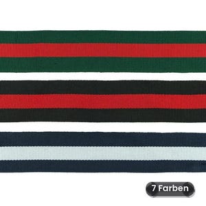 Op de afbeelding: Drie stroken geweven lint met een geribbelde textuur. De bovenste strook is donkergroen met een rode middenstreep. De middelste strook is zwart met een rode middenstreep. De onderste strook is marineblauw met een witte middenstreep. Tekst 7 Farben.