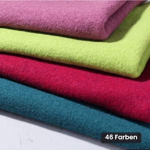 Könnte beinhalten: Vier gefaltete Lagen aus dickem, strukturiertem Stoff in den Farben Magenta, Limettengrün, Dunkelrot und Petrol. Das Material hat eine dichte, filzartige Optik mit sichtbarem Flor. Ein kleines schwarzes Etikett zeigt den Text 46 Farben.