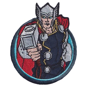 Op de afbeelding: Een geborduurde ronde patch met een figuur met blond haar die een zilveren gevleugelde helm, een donkerblauwe tuniek met zilveren ronde accenten en een rode cape draagt, terwijl deze een grote zilveren rechthoekige hamer vasthoudt.