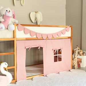 May include: A wooden bunk bed with a pink fabric playhouse attached. The playhouse has a window and curtains. Decorative elements include a white swan, a stuffed bunny, and a giraffe toy.