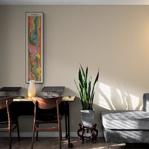 May include: A home office workspace with two desks and chairs, a potted snake plant, and a gray sectional sofa. A framed abstract art print hangs on the wall.