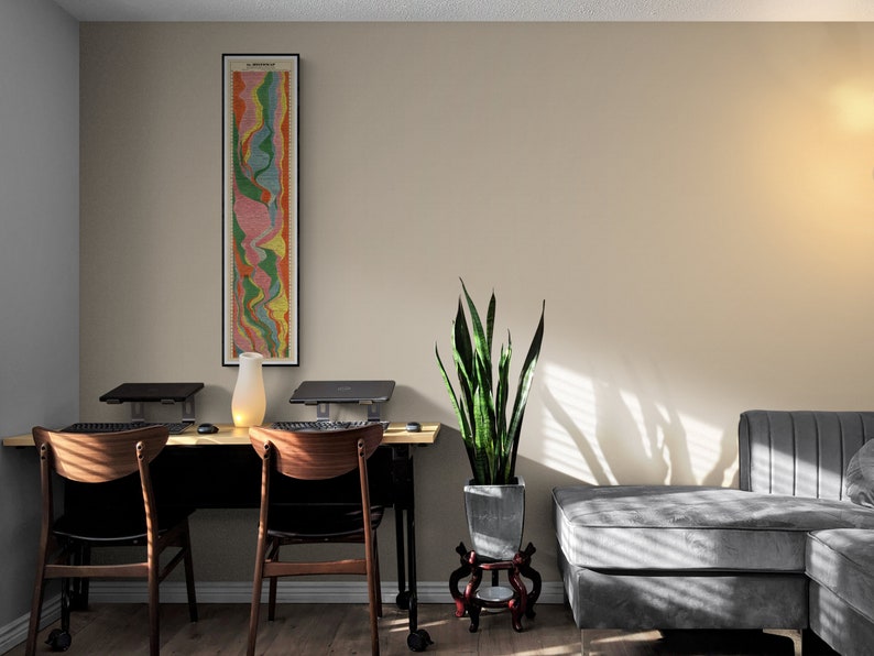 May include: A home office workspace with two desks and chairs, a potted snake plant, and a gray sectional sofa. A framed abstract art print hangs on the wall.