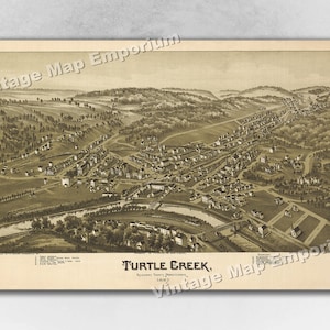 May include: An antique map of Turtle Creek, Pennsylvania. The map shows a bird's eye view of the town, with buildings, streets, and a river. The map is printed in sepia tones and has a vintage look.