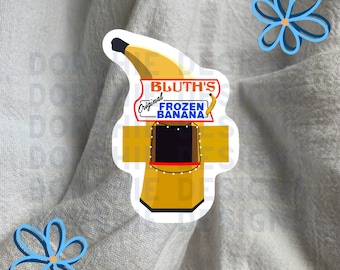 May include: A yellow banana-shaped sticker with a cartoon drawing of a stand that says "Bluth's Original Frozen Banana" in red and white text.