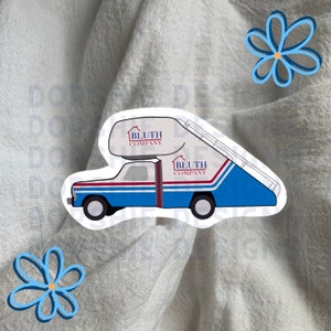 Op de afbeelding: Een witte sticker met een blauwe en rode vrachtwagen met een lift. De vrachtwagen heeft de tekst "Bluth Company" aan de zijkant en op de lift.