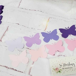 Puede incluir: Una colecci&oacute;n de mariposas de papel en varios tonos de rosa, morado y lavanda. Las mariposas est&aacute;n dispuestas en un patr&oacute;n de degradado, con los tonos m&aacute;s oscuros en la parte superior y los tonos m&aacute;s claros en la parte inferior. Las mariposas son todas del mismo tama&ntilde;o y forma, y tienen un dise&ntilde;o delicado recortado.